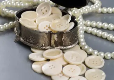 Ivory-coloured bone buttons in a silver box with pearls