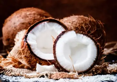 A coconut broken in half on burlap