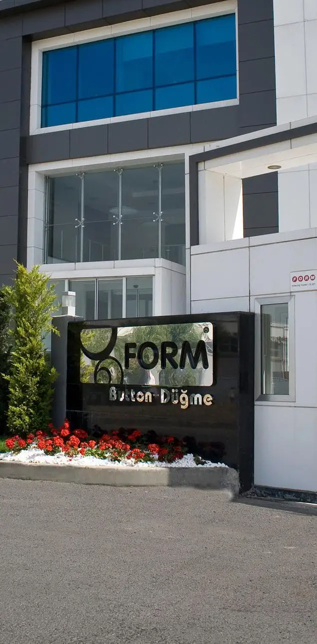 The FORM Button – Düğme sign in black stone at the entrance of the factory, with red flowers