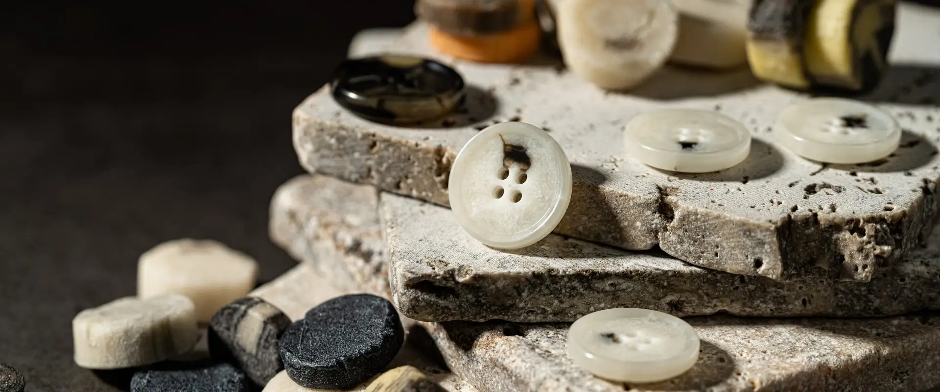 Synthetic buttons in white, grey and black on travertine