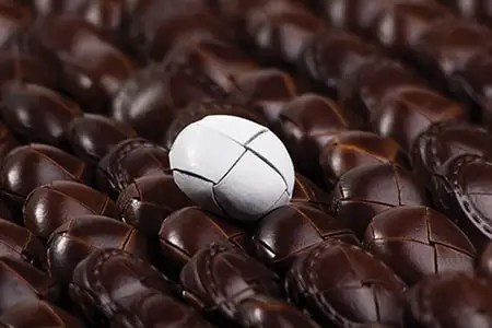 A white woven leather button among dark ones