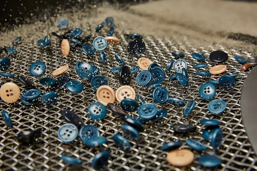Blue and natural buttons on a perforated tray after polishing