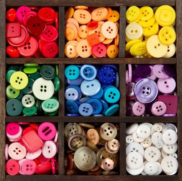 Buttons sorted by colour in a wooden tray