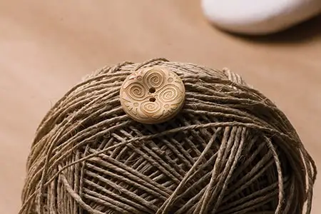 Bir yumak sicim üzerinde oymalı bir tahta düğme